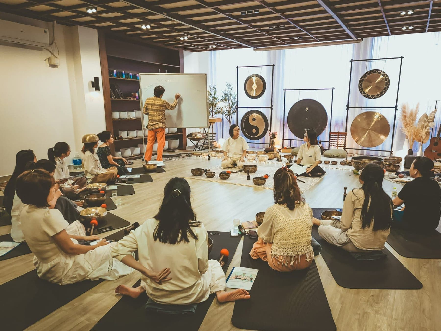 Students practising with singing bowls during a classroom training session