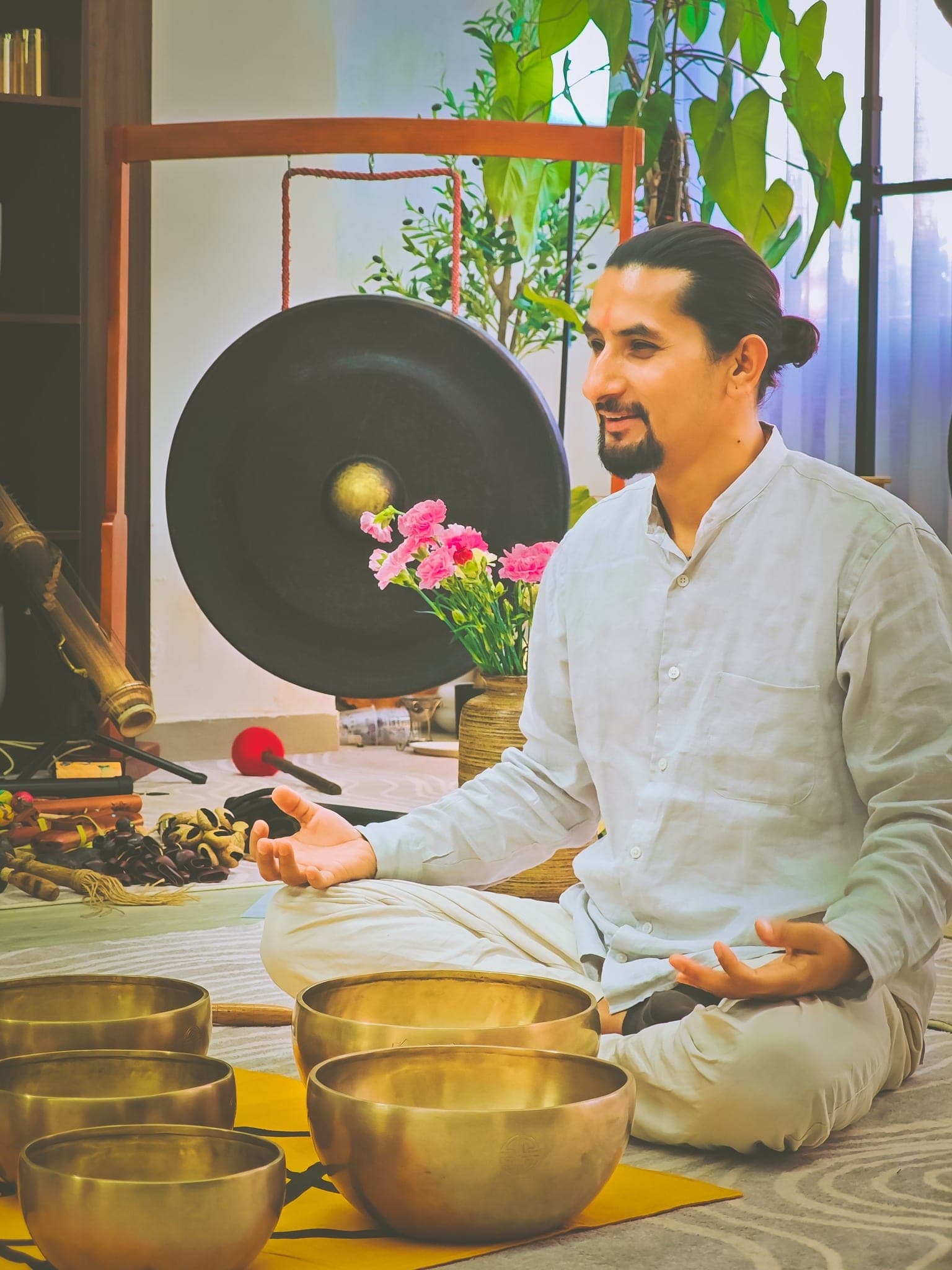 Grand Master Akash Banjara seated beside a gong, smiling