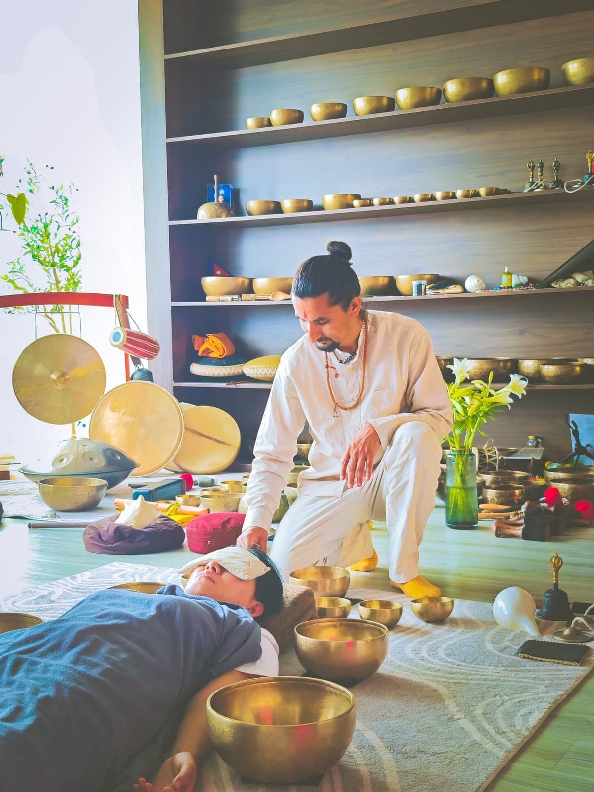 A practitioner arranging singing bowls and gongs around a person during a sound healing session