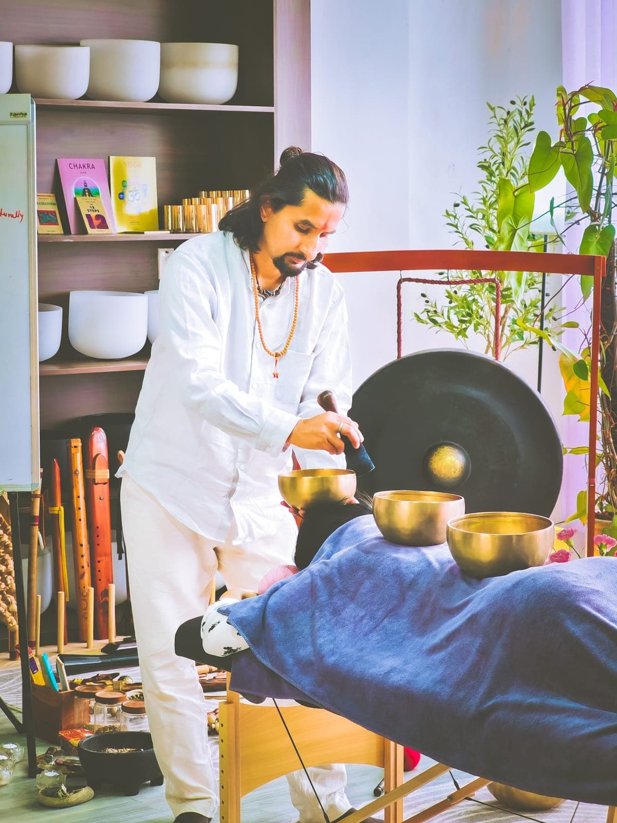 A practitioner playing a large gong over a participant lying down